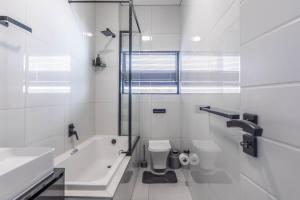 a bathroom with a tub and a toilet and a sink at Greystone Serenity Apartment in Cape Town +35 photos