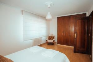 Schlafzimmer mit einem weißen Bett und einem Holzschrank in der Unterkunft Villa Nora in Sanxenxo