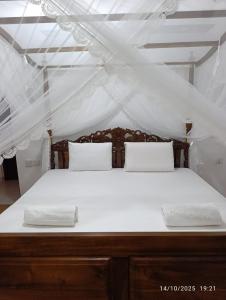 Una cama grande con sábanas blancas y almohadas. en Villa Senowin, en Anuradhapura