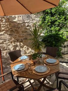 a wooden table with plates and glasses on it at La fleur d'oranger in Aigues-Mortes