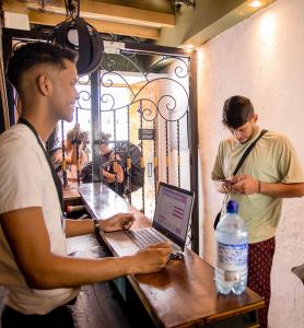 Dos hombres de pie junto a una mesa con una computadora portátil. en Seven Nights Hostel Cartagena, en Cartagena de Indias