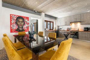 a dining room with a glass table and yellow chairs at Modern Rustic Gem at the foot of Table Mountain in Cape Town