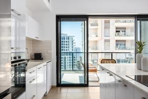 a white kitchen with a view of a city at O&O Group- Modern Luxury APT-Mesmerizing Sea Views in Bat Yam
