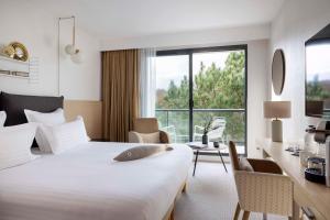 a hotel room with a bed and a large window at Best Western Plus Hotel les Rives du Ter in Larmor-Plage