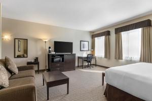 ネルソンにあるBest Western Plus Baker Street Innのベッドとリビングルームがあるホテルの部屋