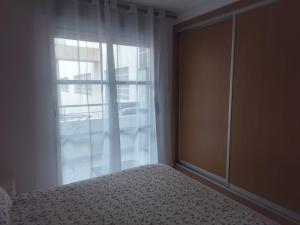 a bedroom with a bed next to a window at Apartamento en playa de Moncofar con wifi y aire acondicionado in Moncófar