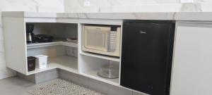 a kitchen with a microwave in a white cabinet at Apê Bella Vista Campos in Campos do Jordão