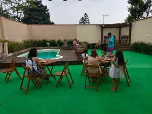 伊塔波阿Sonho Meu的一群人围坐在铺着绿色地毯的桌子旁。