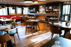 a restaurant with tables and chairs and a library at Best Western Plus Le Conquerant Rouen Nord in Bois-Guillaume