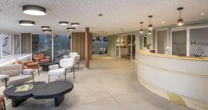 un vestíbulo con una zona de espera con sillas y mesas en Best Western Plus Sanary, en Sanary-sur-Mer