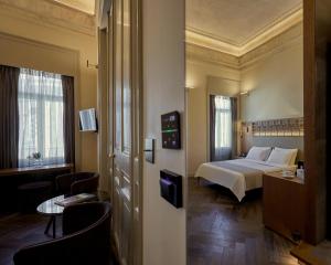 a hotel room with a bed and a table and chairs at Athens 1890 Hotel & Spa in Athens