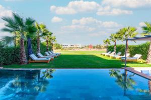 a pool with chaise lounge chairs and palm trees at Luxury Villa with Heated Pool & Private cinema in Marrakesh