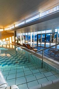 ラムサウ・アム・ダッハシュタインにあるHotel Ramsauhof Pool & Wellness Breakfast & Light Dinner Buffetの建物の中に椅子が置かれたプール