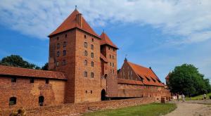 a large red brick building with a tall tower at Apartament w Centrum Malborka in Malbork