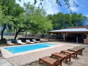 ein Swimmingpool mit Liegestühlen und einem Picknicktisch in der Unterkunft Finca La Huella in Santiago del Estero