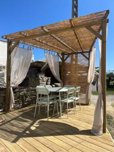 a wooden deck with a table and chairs under a pergola at Maison cosy avec terrasse, à 5 minutes des plages in Porspoder