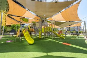a playground with a yellow slide and swings at Oַ&O Group- Luxury Tower 3BR Beach View High Floor in Bat Yam