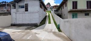 an alley between two buildings with green grass at Apê Bella Vista Campos in Campos do Jordão