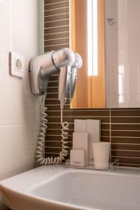 a blow dryer in a bathroom next to a sink at Park Hotel Porto Aeroporto in Maia