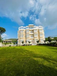 a large white building with a green field in front at Aryavarta A Boutique Abode in Nāi +9 photos