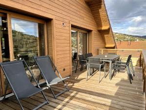 a patio with a table and chairs on a deck at Splendide appartement style chalet classé 4 étoiles, terrasse face à la montagne in La Bresse