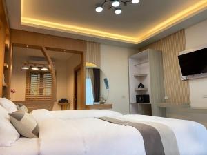 a bedroom with a white bed and a flat screen tv at The Cushty Days Lanta in Ko Lanta