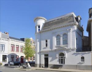 a white building with a clock tower on a street at Architectonisch en kunsthistorisch droomverblijf in Antwerpen in Antwerp