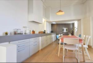 a kitchen with white cabinets and a table and chairs at Architectonisch en kunsthistorisch droomverblijf in Antwerpen in Antwerp