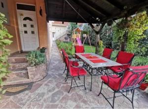 um pátio com cadeiras vermelhas e uma mesa num pátio em Vila Miona Apartments em Belgrado