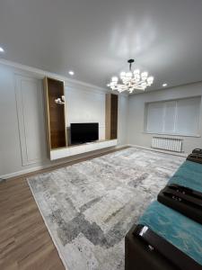 sala de estar con cama y TV de pantalla plana en 3 комнатный апартамент на Батыс 2, en Aktobe