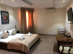 a bedroom with a bed and a desk and a television at nur m hotel in tashkent in Yakkasaray