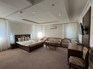 a bedroom with a bed and a couch and a table at Nur m hotel Free transfe hotel in airoport in Yakkasaray +6 photos