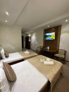 a hotel room with two beds and a desk at nur m hotel in tashkent in Yakkasaray