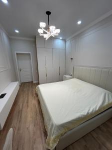 Un dormitorio con una cama blanca y una lámpara de araña. en 3 комнатный апартамент на Батыс 2, en Aktobe 15 fotos más