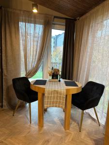 a dining room table with two chairs in front of a window at Hugo Airport in Mārupe