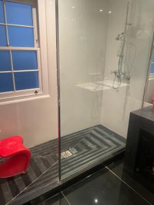 a shower with a red chair in a bathroom at 1 callcoot Road in London +18 photos