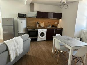 a living room with a kitchen and a table with chairs at Appartement moderne proche de l'autoroute in Combronde