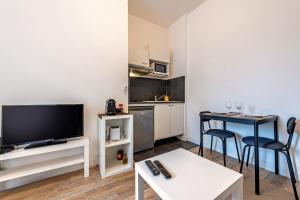 a living room with a television and a table with chairs at Les Capucins - T2 tout confort in Brest