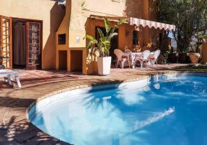 a swimming pool in front of a house with a table and chairs at Oh so Heavenly in Cape Town