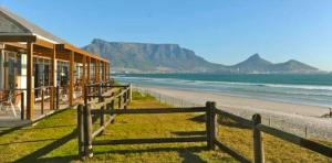 a fence next to a beach with mountains in the background at Oh so Heavenly in Cape Town