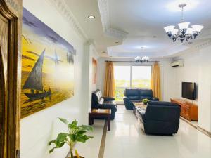 a living room with blue furniture and a painting of a boat at Two- Bedroom Masaki Sea View Retreat in Dar es Salaam