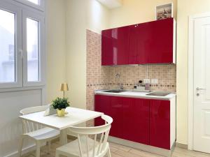 a kitchen with red cabinets and a white table at Dimora dei Mercanti Suites in Turin