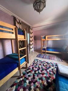 a bedroom with two bunk beds and a rug at Surf capitain in Tamraght Ouzdar