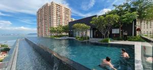 deux personnes nageant dans une piscine à côté d'un bâtiment dans l'établissement Urban Suites Georgetown Penang - Affordable & Cozy Stay with High Floor-Sea & Penang Bridge View, à George Town