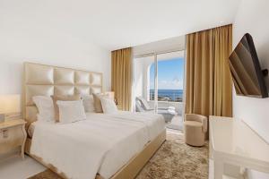 ein weißes Schlafzimmer mit einem großen Bett und einem großen Fenster in der Unterkunft Portals Hills Boutique Hotel in Portals Nous + 64 Fotos