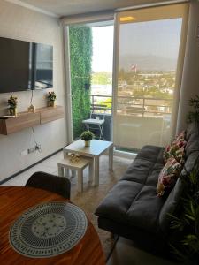 a living room with a couch and a large window at innovador departamento cercano a mall y carretera in Rancagua