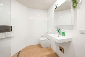 a white bathroom with a sink and a toilet at 803 - Stylish Retreat - Ocean Views & Parking in Newcastle