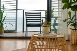 a rattan table with a chair in a room with plants at 803 - Stylish Retreat - Ocean Views & Parking in Newcastle