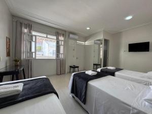 ein Hotelzimmer mit zwei Betten und einem Fernseher in der Unterkunft Hospedar Imperial in Campina Grande