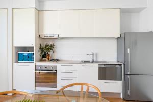 a kitchen with white cabinets and a stainless steel refrigerator at 901 - Perfect Penthouse - With Free Parking in Newcastle